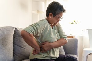 A woman sitting down with back conditions.