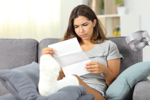 An upset woman with a cast looking at a paper.